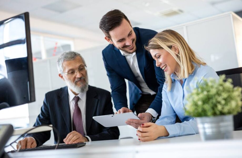 Smiling,Young,Manager,Helping,Senior,Worker,With,Funny,Computer,Work